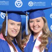 Two friends pose together in cap and gown at Gradfest